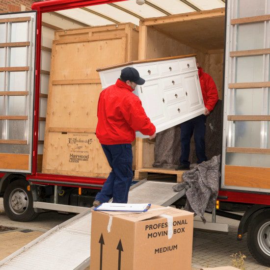 move team staff carrying a white sideboard onto a lorry in brockenhurst