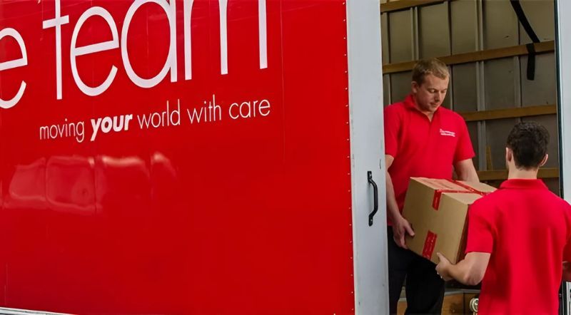 move team staff carrying a box off a van