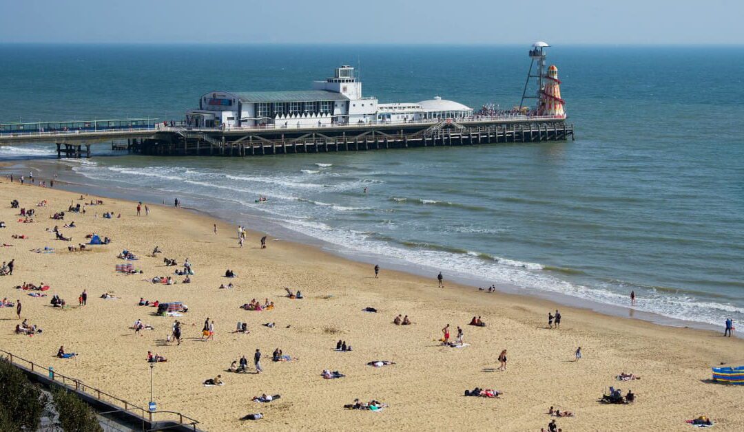 Sunny view of Bournemouth Beach, Dorset and Bournemouth Pier with people on the sand
