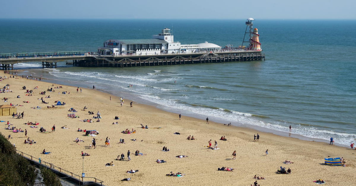 Sunny view of Bournemouth Beach, Dorset and Bournemouth Pier with people on the sand